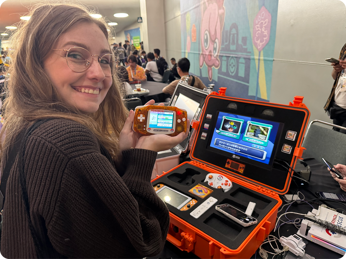 A Pokémon Fan holding up a Gameboy Advance system displaying the Pokémon Celebi.